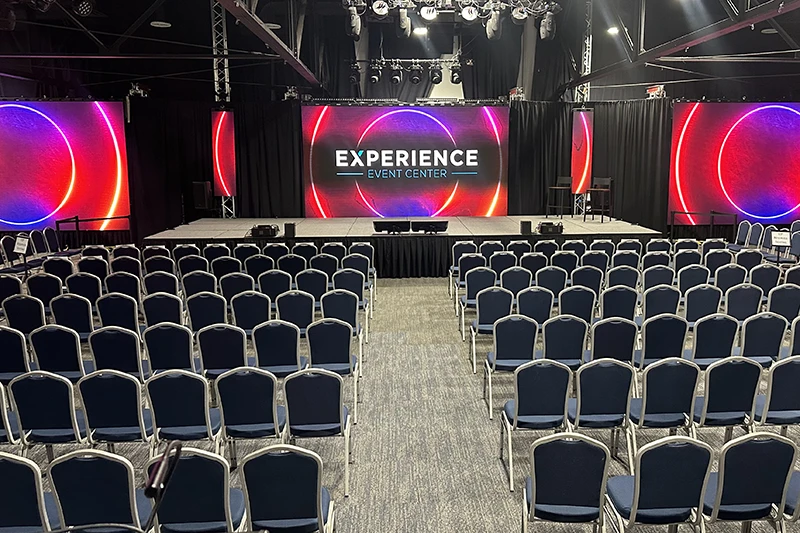 Event Center set up with a stage, large screens, and many chairs