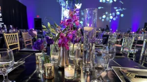 A table setting at a gala including ambient lighting, florals, candles and fine dishes.